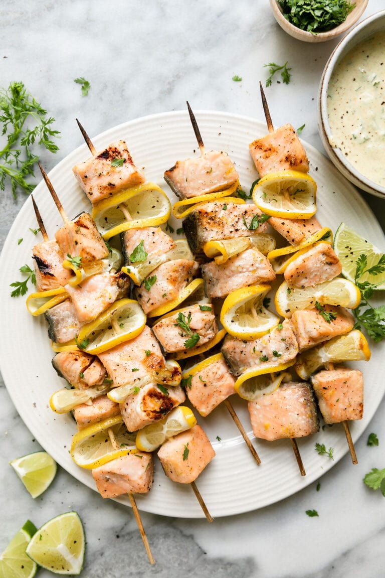 Overhead view plate filled with grilled salmon kabobs with curry yogurt sauce on the side.