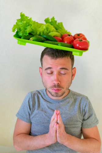 man praying holding vegetable tray on head