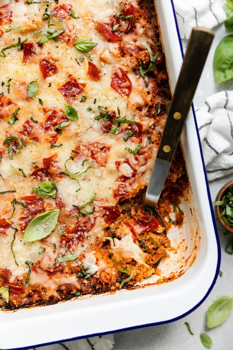 Pepperoni pizza quinoa casserole in baking dish with spoon in casserole for serving.