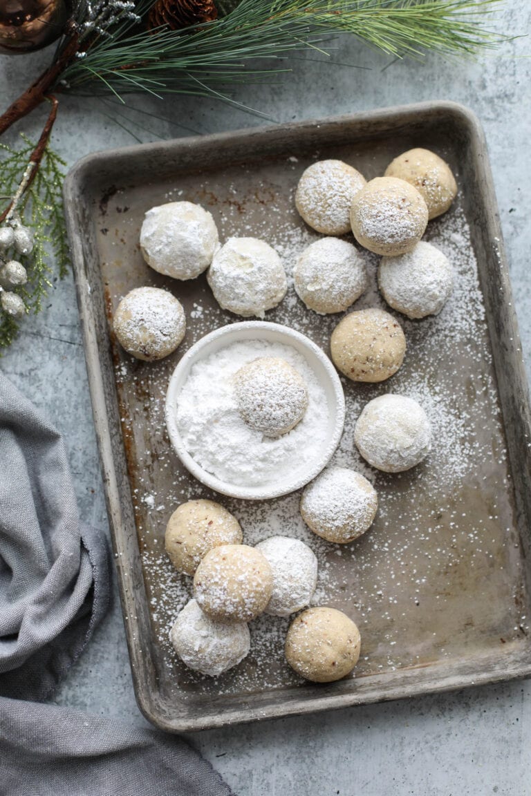 A baking sheet filled with Snowball cookies covered in powdered sugar.