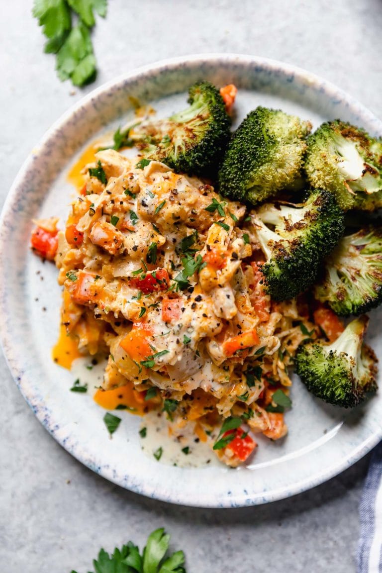Serving of creamy buffalo chicken casserole on plate with roasted broccoli.