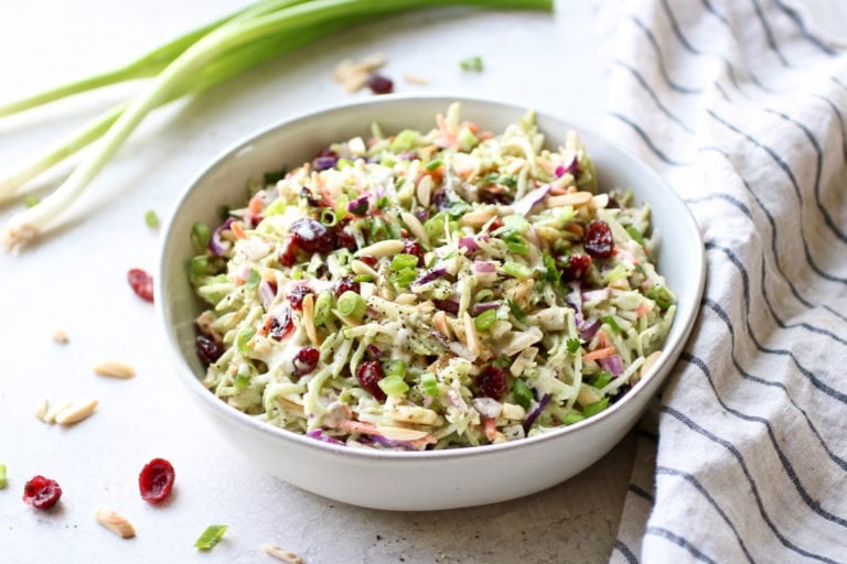 Overhead view white bowl filled with creamy ranch broccoli slaw with dried cranberries.