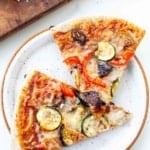 two roasted veggie pizza slices on white spreckled plate