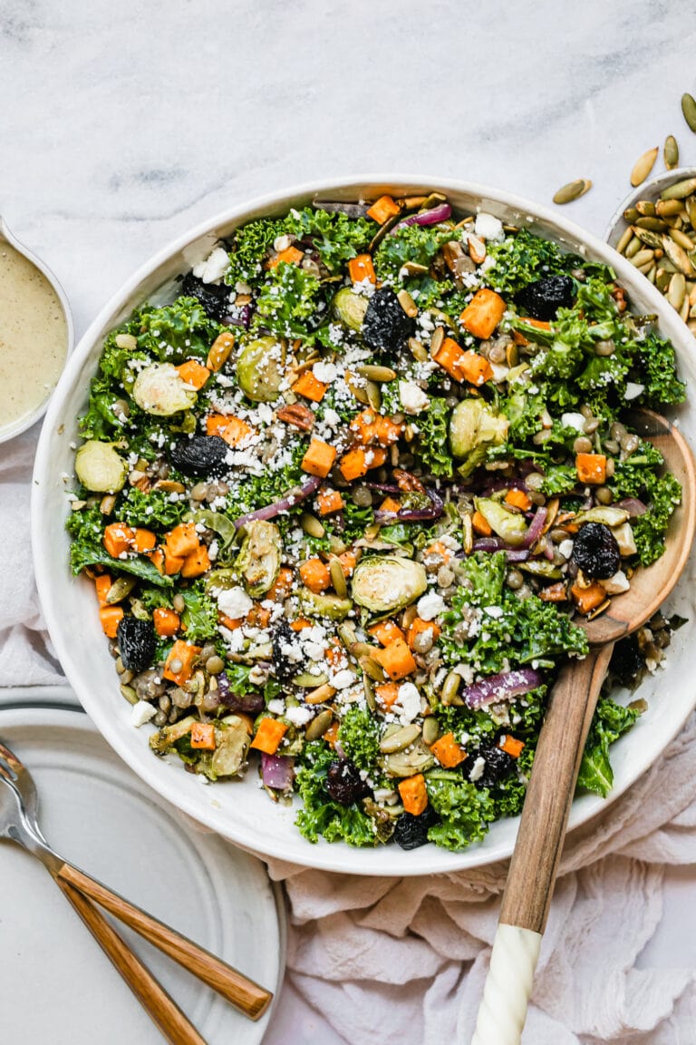 Overhead view lentil salad with roasted vegetables in serving bowl topped with feta cheese